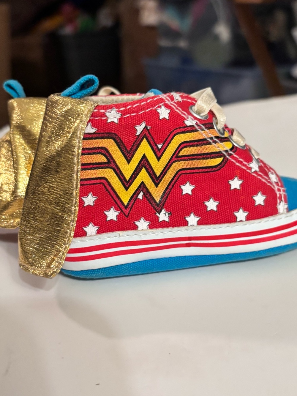DC Comics baby sneaker with Wonder Woman logo. Red canvas with Gold Capes.